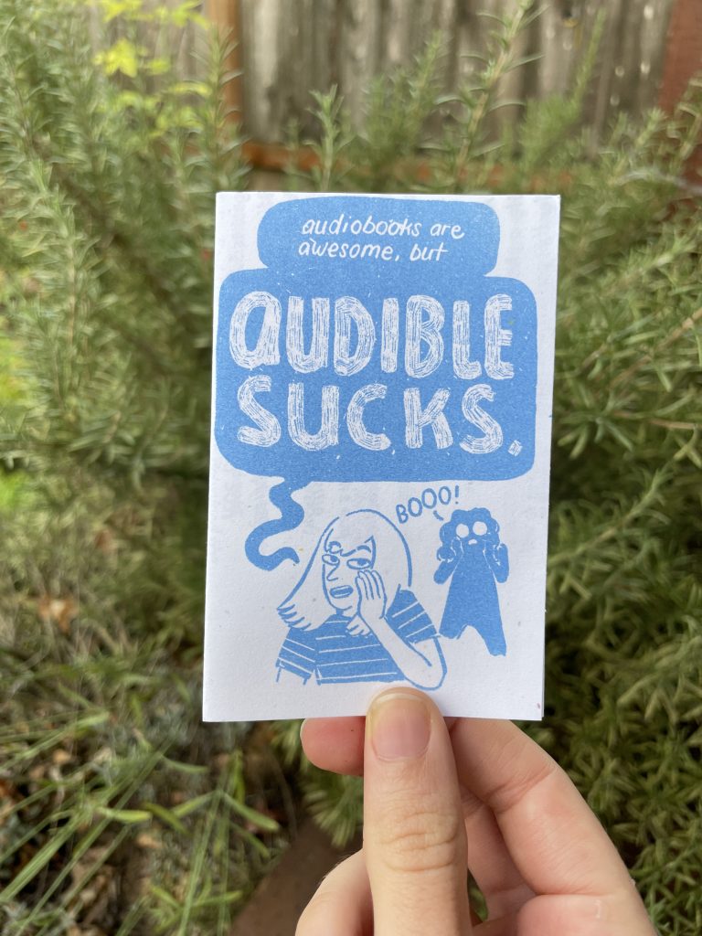 cover: a blue risograph print, forground is Allia a girl with bangs, background is Audra. Allia: "audiobooks are awesom, but AUDIBLE SUCKS" Audra: "boooo!"